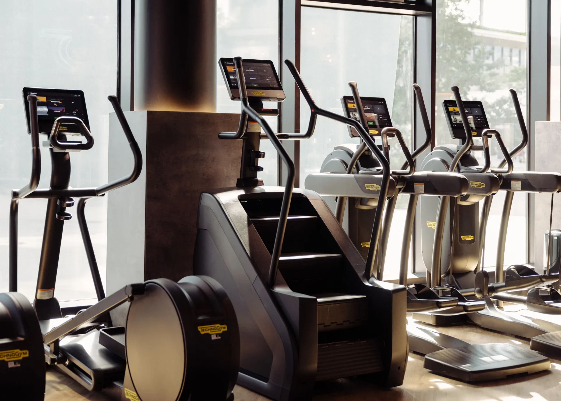 Close-up of stair climber and cardio machines by large windows at EVO Fitness