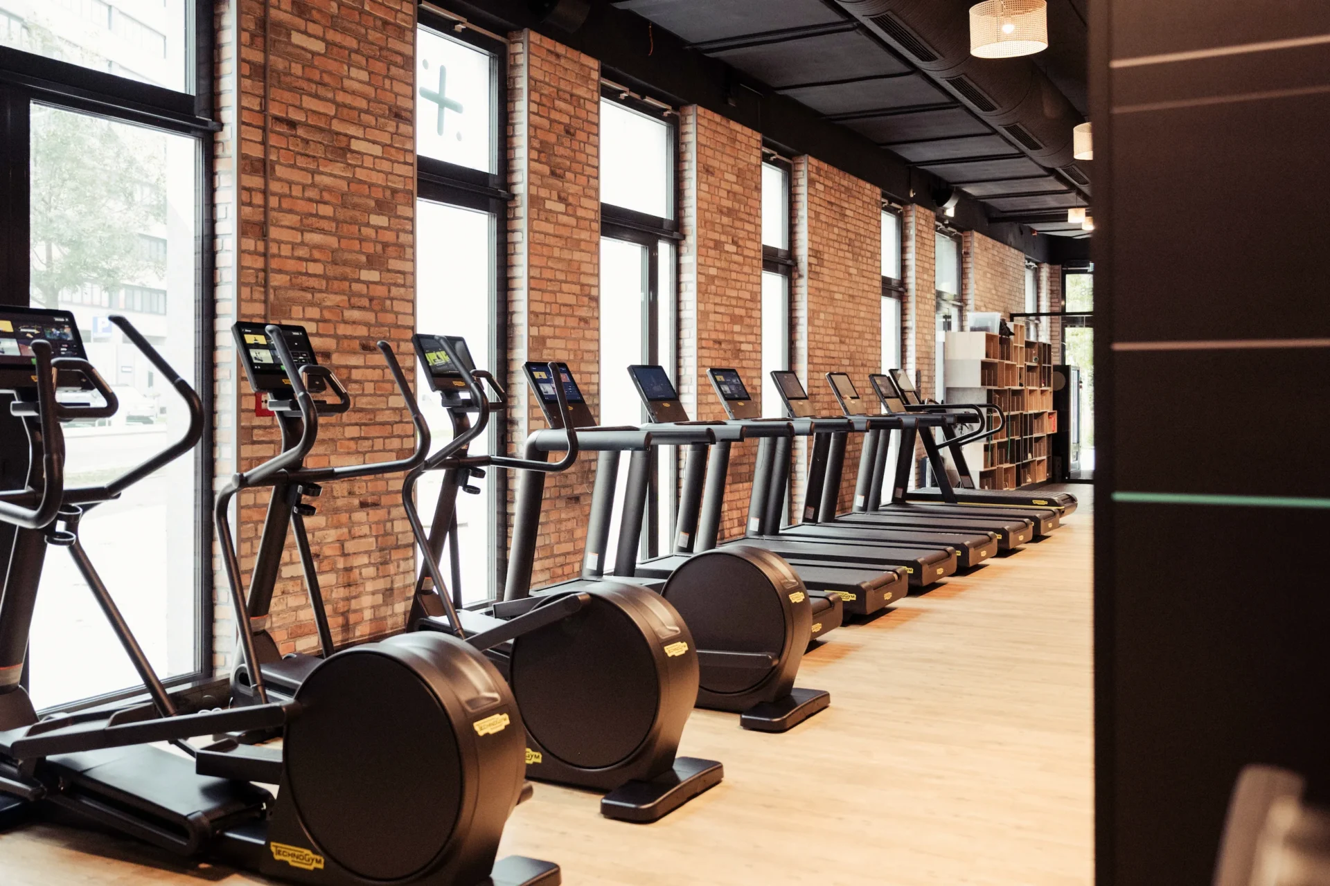 Row of Technogym ellipticals and treadmills in brick wall studio at EVO