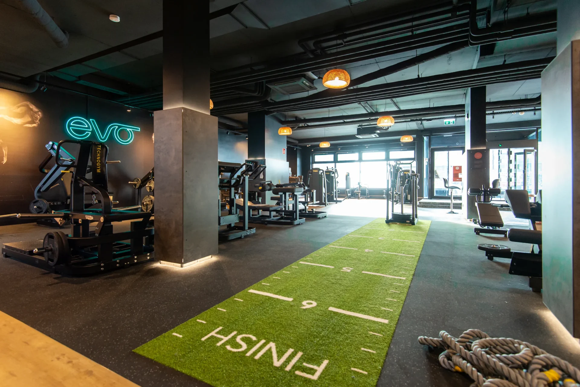 Green indoor turf track with gym equipment and EVO logo wall