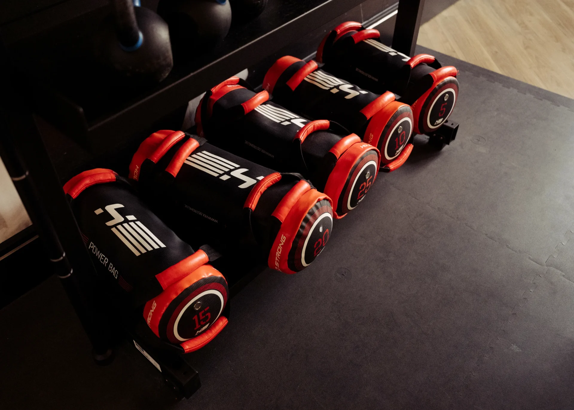 Power bags and kettlebells neatly arranged on a rack at EVO Fitness