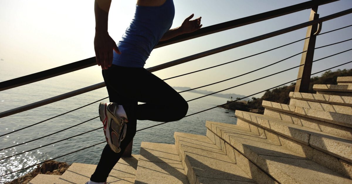Woman running up stairs next to a beach