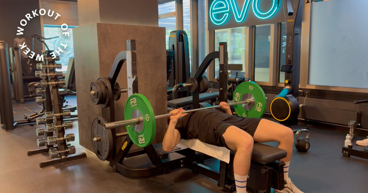 Workout of the week: 35-min hybrid conditioning workout - Man performing bench press with barbell in modern EVO gym with strength equipment