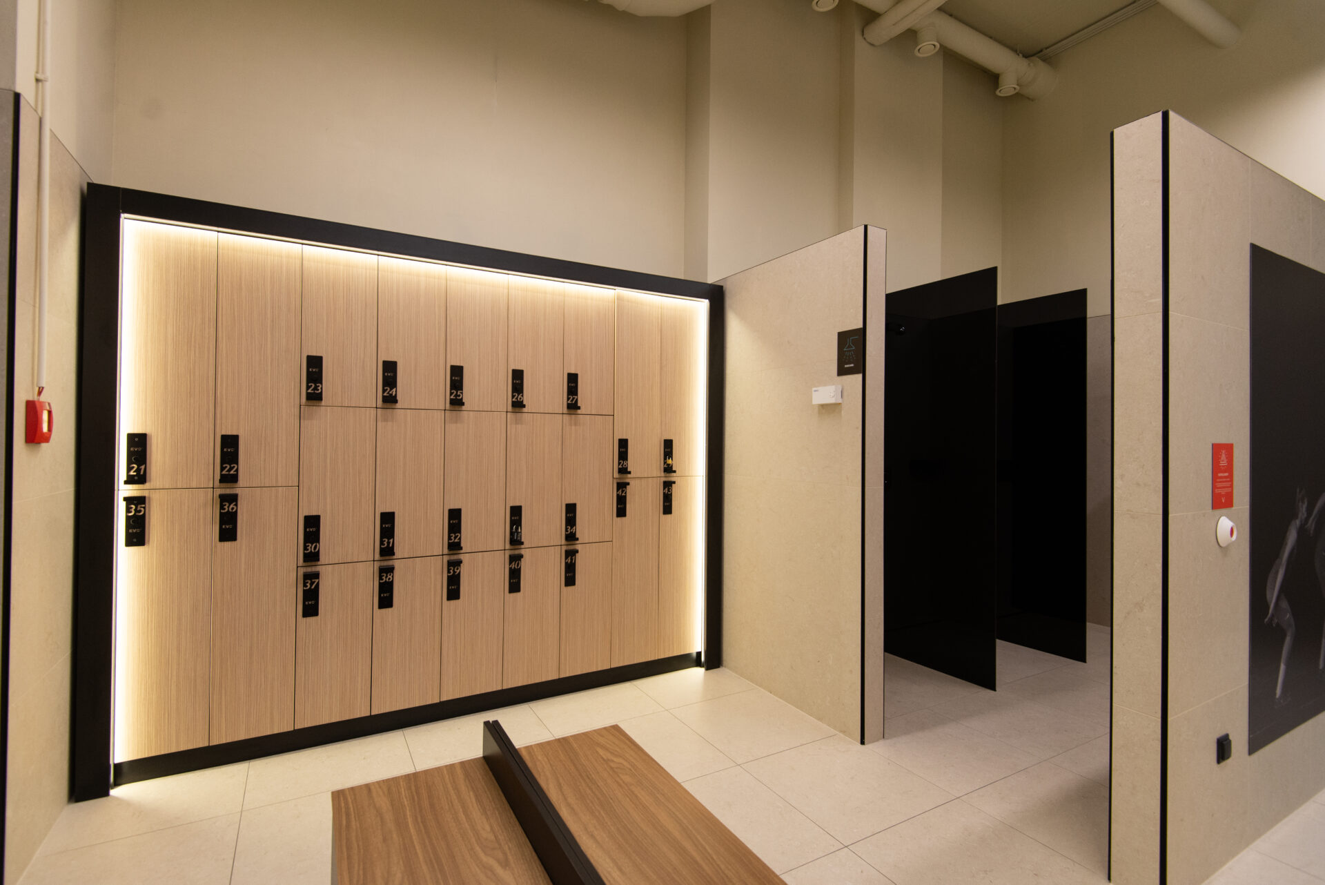 Modern EVO Fitness locker room with light wood lockers and black shower area